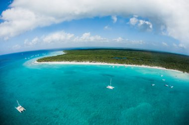 Punta Cana manzarası, Bavaro, Saona, Cap Cana tropikal okyanus denizi ve Dominik Cumhuriyeti 'ndeki turist ve teknelerle Karayip kıyılarındaki palmiye ağaçları üzerindeki plaj insansız hava aracı görüntüsü.  