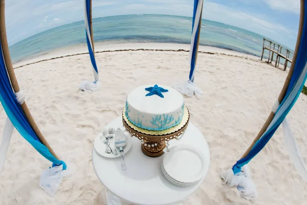 Wedding cake decorated for bride and groom to cut during tropical destination caribbean wedding marriage outdoor ceremony on the sandy beach in Dominican republic