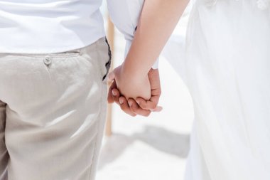Newlyweds at the wedding romantic couple holding hands during destination wedding marriage matrimonial ceremony on the sandy beach in Dominican republic, Punta Cana. Family, love, unity concept.   clipart