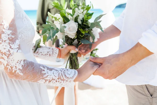 Newlyweds at the wedding romantic couple holding hands during destination wedding marriage matrimonial ceremony on the sandy beach in Dominican republic, Punta Cana. Family, love, unity concept.