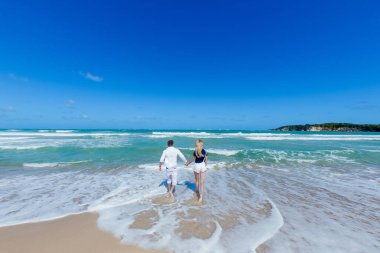 Aşk yaşayan romantik bir çift, balayı tatillerinde kumsalda sarılıp, öpüşüp, koşuyor. Dominik Cumhuriyeti 'ndeki Karayip manzarası Punta Cana 