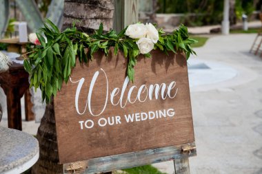 Wooden welcome table board sign at the wedding on the beach with welcoming romantic words during destination wedding marriage ceremony, invitation for the guests clipart