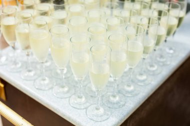 Şampanya köpüklü şarap şişesi ve bardaklar açık havada düğün yemekleri bardağa dökülüyor ve el ele tutuşuyorlar. Parti ve kutlama..