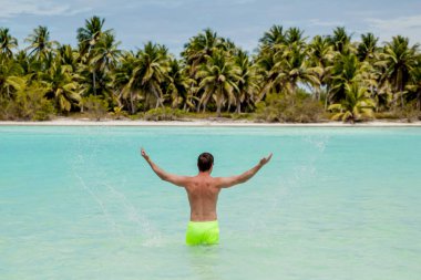 Dominik Cumhuriyeti 'nin Saona adasında beyaz kum, mavi su ve palmiye ağaçları olan tropikal manzaranın tadını çıkaran Karayip sahilinde duran bir adam. Özgürlük kavramı