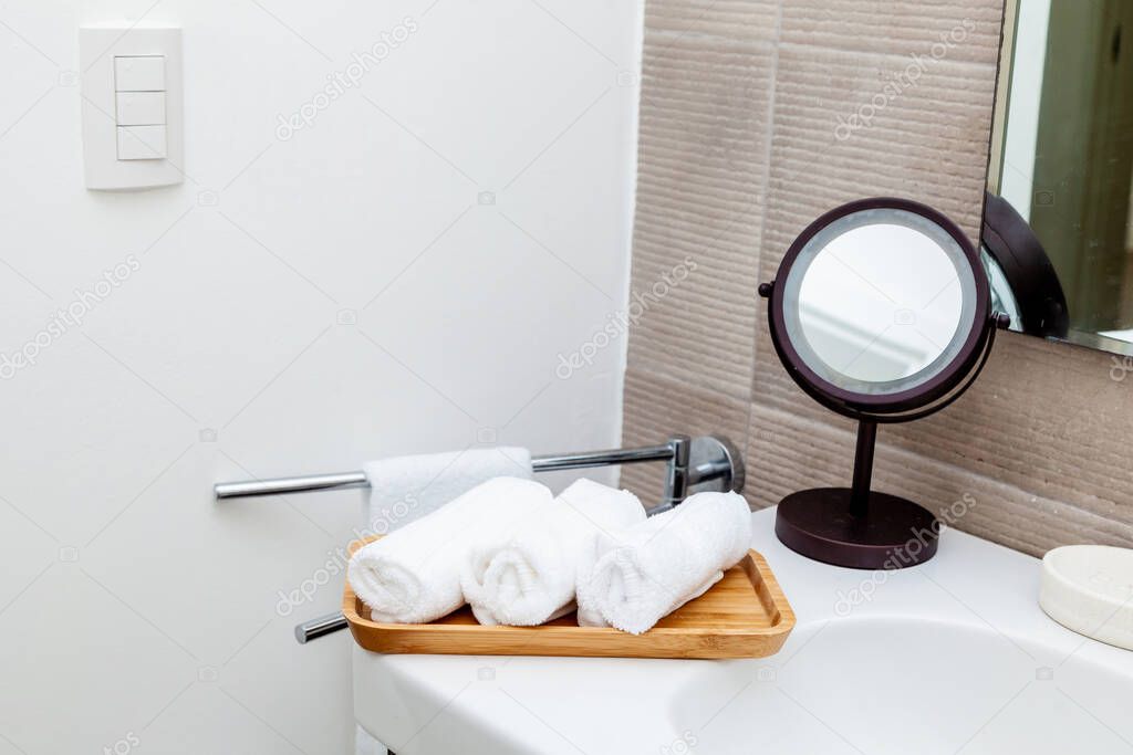 Rolled bath towels white and blue laying on the shelf in spa bathroom decorated with anchor and plant in home interior 