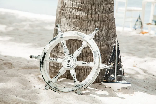 Decoratief Wit Houten Jacht Stuurwiel Liggend Het Zand Onder Palmboom Rechtenvrije Stockafbeeldingen