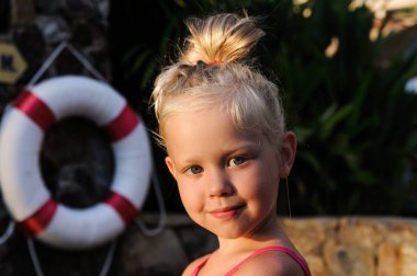 hayat şamandıra arka plan üzerinde havuz kenarında küçük bir kız portresi