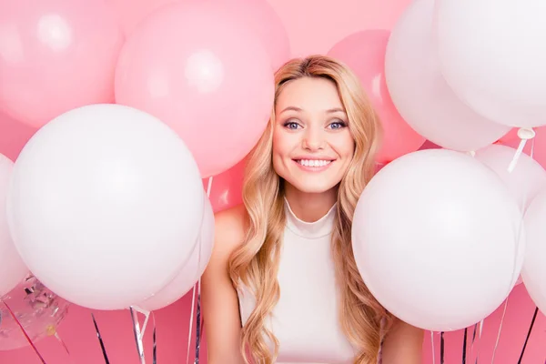 一个欢快的孩子气的女孩的肖像与许多白色的空气气球周围看着在粉红色背景隔离相机 — 图库照片