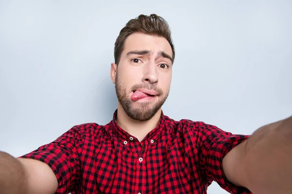 Don\'t be shy! Close up portrait of excited sincere openhearted emancipated handsome guy fooling around on camera and taking selfie, isolated on gray background