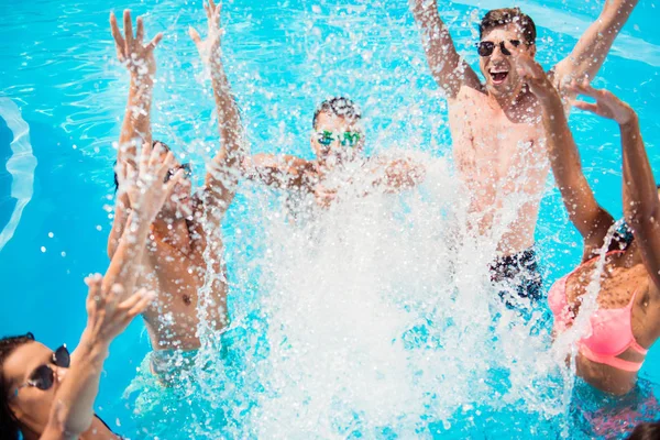 Cropped close up shot of youth going crazy in the pool, splitting water and go insane, huge splashes of blue clear water, guys jump and dabbl
