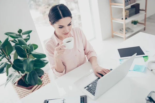 High angle view of attractive woman in classic outfit having mug with coffee typing on keypad keyboard surfing internet chatting with friends enjoying pause time out recreation in modern office