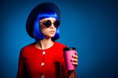 Advertisement concept. Portrait with copy space empty place of thoughtful woman having mug with tea latte cappuccino in hand isolated on blue background clipart