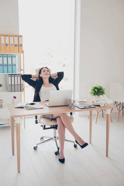 Full size portrait of sexy trendy woman wearing high heel shoes skirt sitting in modern office holding hands behind head planning vacation weekend trip journey