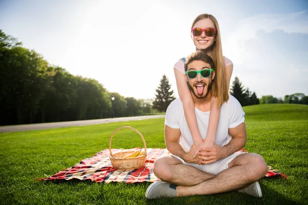 Togetherness trust support concept. Portrait of stylish trendy couple having recreation outside sitting on green grass with beautiful landscape looking at camera enjoying sunny day