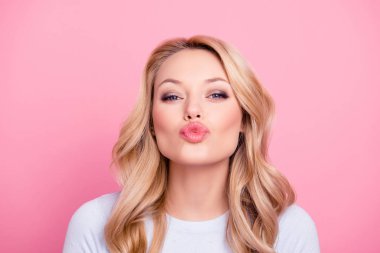 Portrait of cute lovely girl in casual outfit with modern hairdo sending blowing kiss with pout lips looking at camera  isolated on pink background. Affection feelings concept clipart