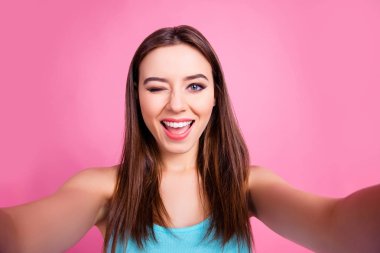 Close up photo of playful cute lovely gorgeous stylish trendy charming female student with long brown straight hair giving a wink and taking selfie, isolated om pink background clipart