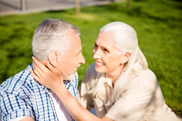 Portrait of beautiful sweet couple making picnic outside sitting on green grass enjoying time together looking at each other. Love story true feelings concept