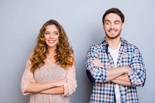 Portrait of funny comic couple holding arms crossed looking with eyes at each other having beaming smiles isolated on grey background