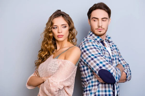 Portrait of upset unhappy couple standing back to back holding arms crossed ignoring each other isolated on grey background