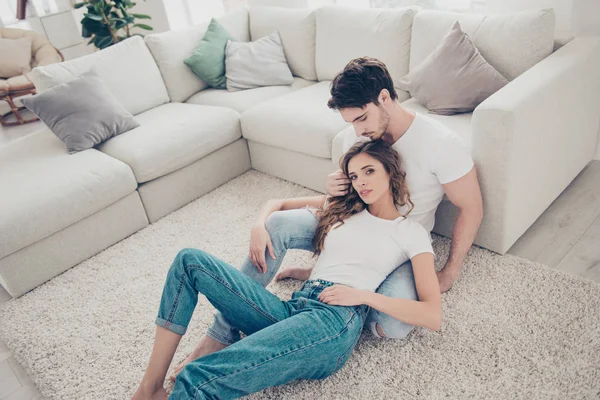Portrait of stylish trendy students in denim clothes white t-shirts enjoying time together in modern living room sitting on floor. Lifestyle style concept