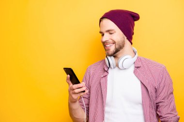 Profile side half-faced close up portrait of handsome excited cheerful joyful satisfied glad guy with toothy beaming smile using smartphone in hands listening to track tunes isolated background clipart