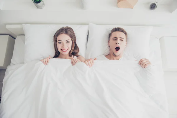 年轻有吸引力的昏昏欲睡的情侣的肖像在床上醒来的早晨 覆盖着毯子 女孩微笑着 男人打呵欠 上方高角度视图 — 图库照片