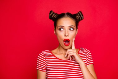 OMG! Close up face of shocked astonished girl with modern hairdo having wide open mouth and brown eyes looking at camera and to touch her cheek by finger isolated on red background with copyspace clipart