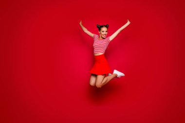 Full-length full-size view of jumping laughing and happy woman dressed in colourful bright clothes isolated on red background clipart