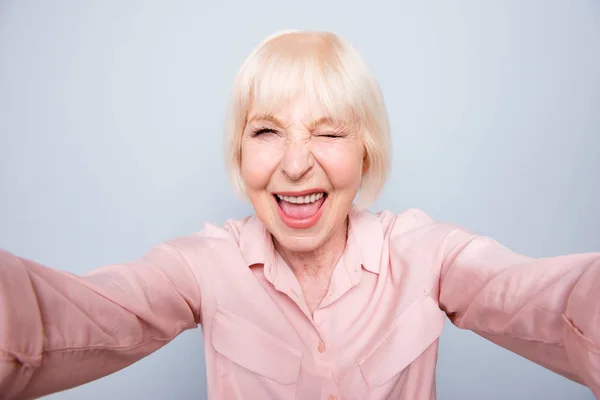 古いアダルト金髪うれしい陽気な白人女性の笑みを浮かべて 撮影肖像画の分離カメラ まばたき 灰色の背景の上に Selfie を行う — ストック写真
