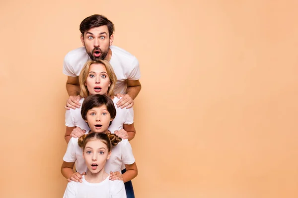 Adorable attractive surprised family, bearded father, blonde mother, boy and girl wearing white T-shirts, standing in odrer of hierarchy, holding hands on each other's shoulders. Copy space — Stock Image Adorable Attractive Surprised Family Bearded Father Blonde Mother Boy Girl Stock Photo