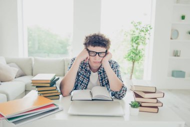Handsome curly-haired tired young guy student at home, nerd, wearing casual, glasses, studying clipart