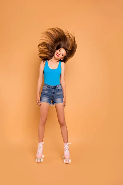 全身桃パステル背景に分離された彼女の髪を振りカメラに探しているキュートで面白い女の子の履くローラー スケートの垂直肖像画 — ストック写真