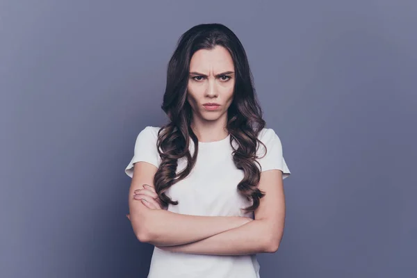 Retrato de chica bonita y elegante de pelo rizado triste en camiseta blanca casual, manos cruzadas, aislado sobre fondo gris — Foto de Stock