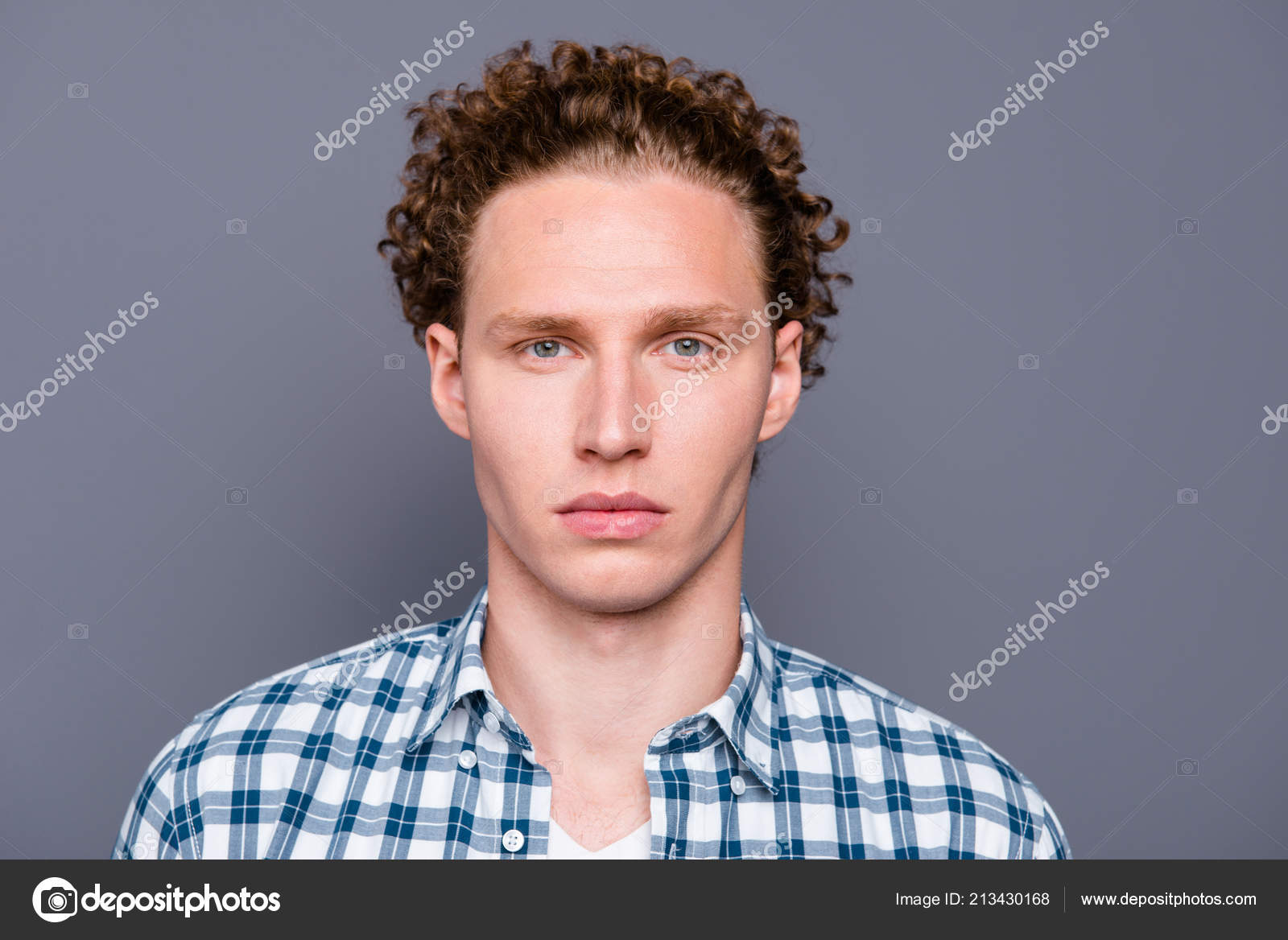 Um homem sério e bonito com cabelo encaracolado e camisa xadrez