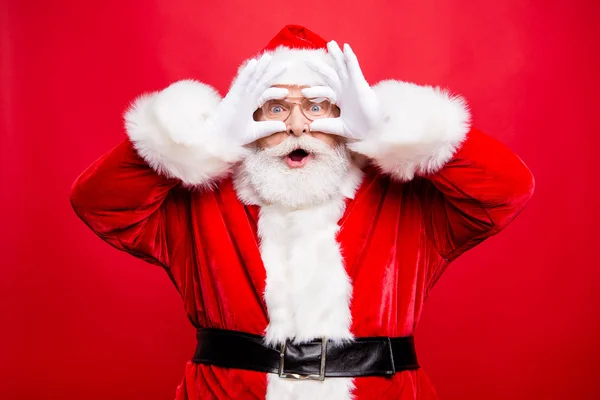 希望成真 惊讶时尚岁的圣诞老人在服装手套头饰与白胡子印象难以置信的脸看着相机站在闪亮的红色背景上隔离 — 图库照片