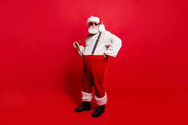 Full length body size of nice calm peaceful Santa pulling suspender preparing to feast festive party promo sale discount isolated over red background