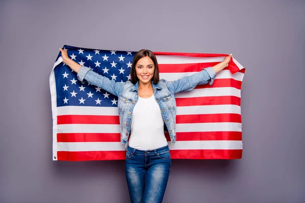 Söt söt härlig självsäkra leende student lady emigrant holding Usa amerikanska flaggan bakom ryggen, bär casual jeans denim, isolerade över grå bakgrund — Stockfoto