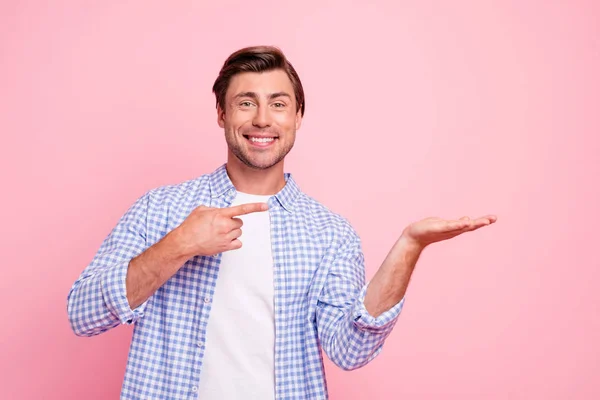 Portret van aardige leuke aantrekkelijke knappe vrolijke vrolijke positieve vent dragen gecontroleerd shirt wijzende vinger palm object geïsoleerd over roze pastel achtergrond — Stockfoto