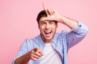 Close-up portrait of his he nice attractive handsome cheerful cheery guy wearing checked shirt showing horn pointing at you mocking isolated over pink pastel background clipart