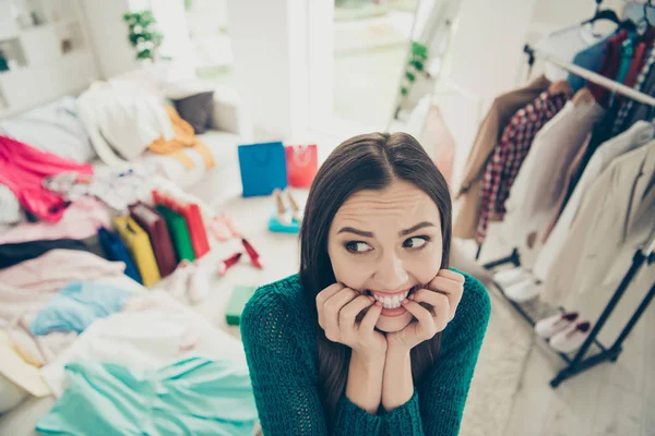 Primer plano retrato de agradable lindo atractivo divertido incierto chica preocupada entre diferentes ropa difícil elección problema en vestidor interior blanco claro —  Fotos de Stock