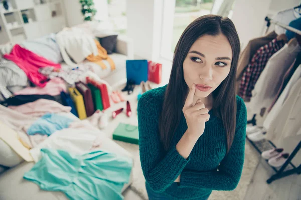 Portret van mooie leuke aantrekkelijke mooie charmante vrij minded meisje onder verschillende kleren moeilijke keuze probleem vraag aanraken van de lippen in lichte witte interieur kleedkamer — Stockfoto