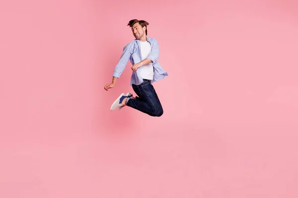 Фотография в полный рост, на которой он прыгает высоко с ума, его красивый взгляд на пустое пространство радует танцующих ди-джеев, звучит музыка в случайных джинсах и рубашке на розовом фоне — стоковое фото