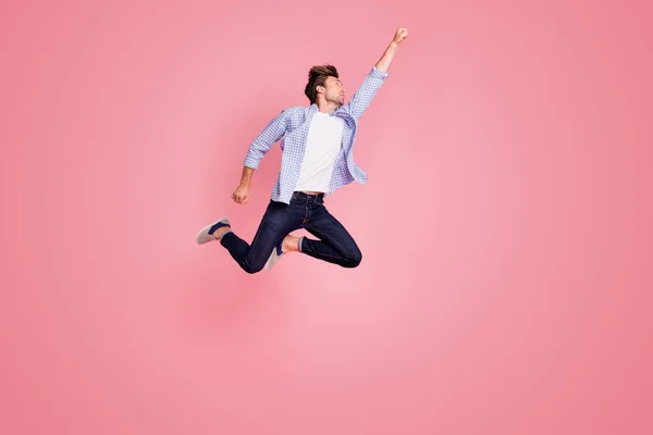 Full length body size photo of jumping high he his him I save world handsome flight up fist raised superman pose shape mood wearing casual jeans checkered plaid shirt isolated on rose background