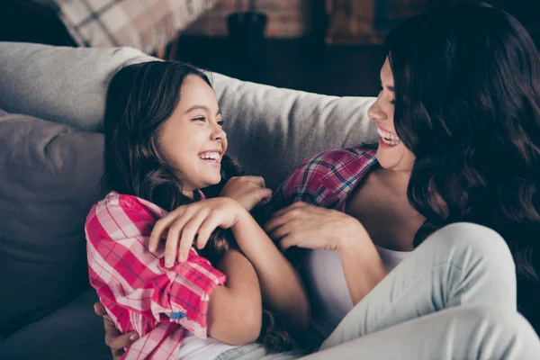 Закрыть фото двух человек мама маленькая дочь сверх радостно свободное время общаться щекотно смотреть похожий досуг радоваться носить розовую клетчатую рубашку джинсы яркий плоский номер квартиры сидеть на уютном диване — стоковое фото