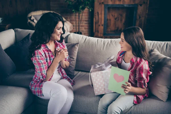Close up side profile view photo two people mum little daughter giving present box card with mommy poem unexpected sweet cute wear pink plaid shirts flat apartment room sit cozy couch divan — стоковое фото
