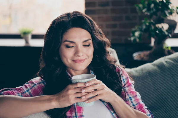 Close-up portret verbazingwekkend prachtig krullend brunette cup armen handen ze haar dame ogen gesloten comfortabele leunend op kussens, het dragen van jeans en geruite geruite overhemd zittend op comfortabele sofa divan — Stockfoto