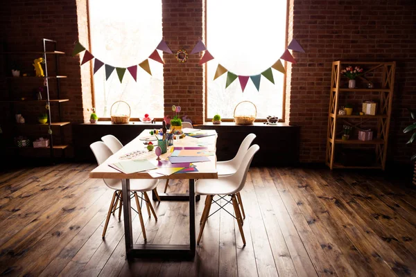 Table avec quatre places assises et carton coloré papier avec des œufs peints dans un spacieux loft en bois intérieur industriel — Photo