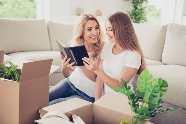 Närbild foto två personer Mamma tonåring dotter storlåda redo ändra plats distraherad på e-bok behöver veta romanen sista slitage vita t-shirts jeans i ljusa platt sitta framför bekväm soffa golv matta — Stockfoto