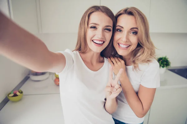 Autorretrato de dos lindas adorables encantadoras encantadoras encantadoras alegres y alegres fascinantes damas rubias mostrando signo v divirtiéndose en la moderna habitación interior blanca clara — Foto de Stock