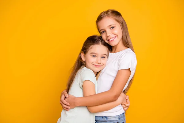 Portrait of two nice-looking cute adorable sweet attractive lovely pretty cheerful positive healthy straight-haired girls cuddling isolated over bright vivid shine yellow background — Stock Photo, Image